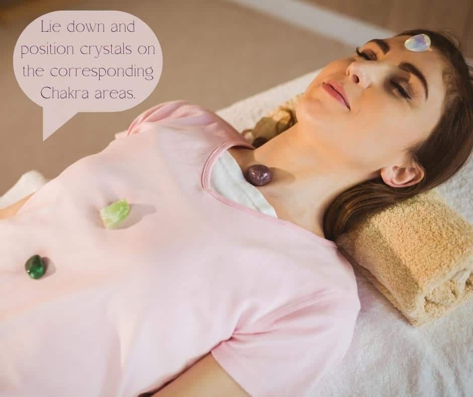 A lady lying down with crystals placed in the chakra areas