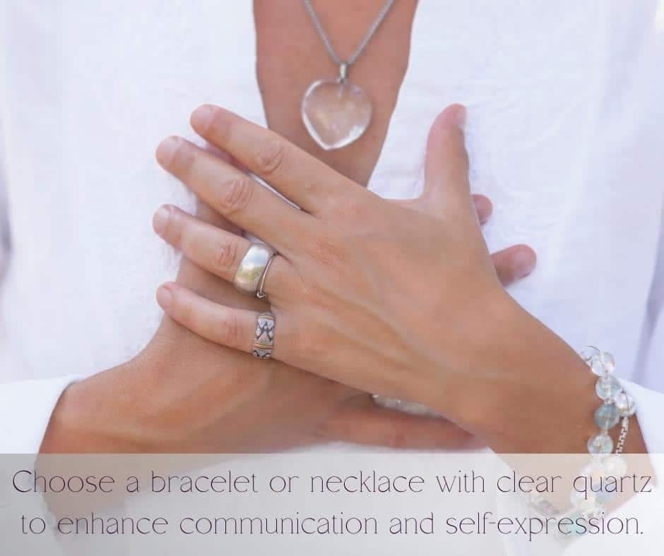 A picture of a ladies hands to her chest with a quartz crystal heart necklace